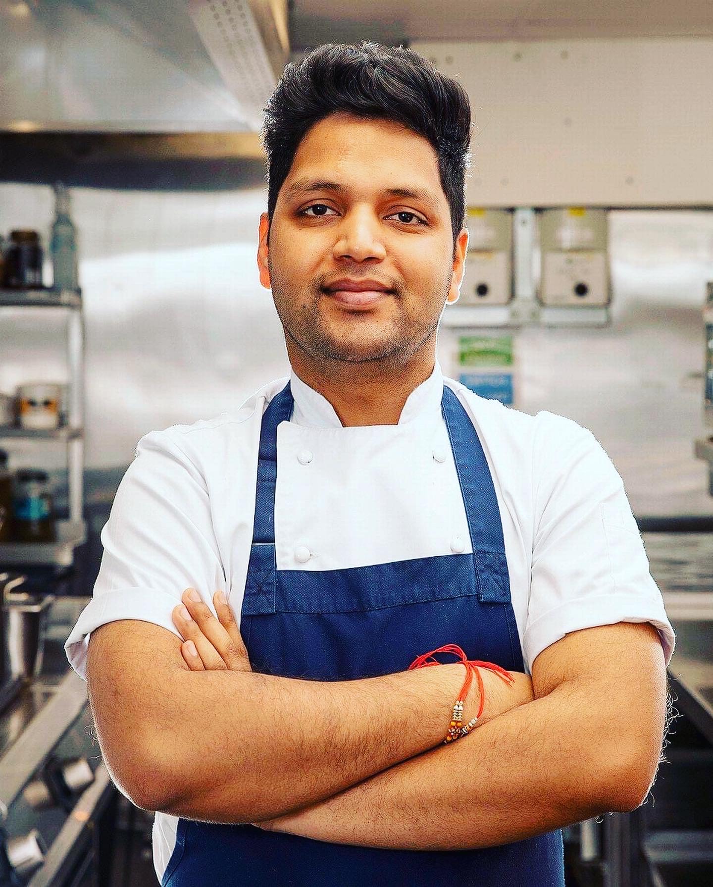 Male in a white chef's jacket with arms crossed looking directly into the camera